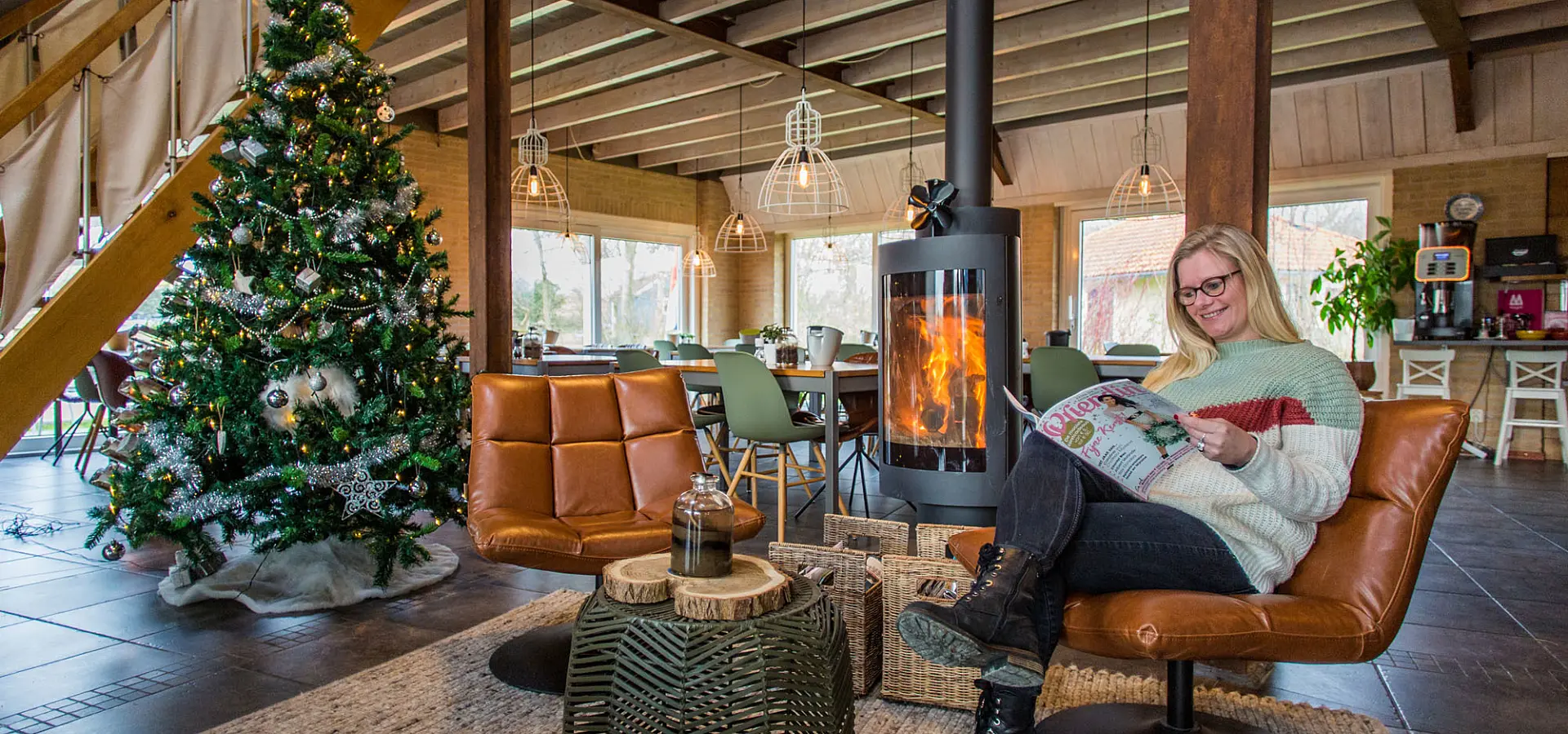 Vrouw in comfortabele stoel met tijdschrift bij open haard in Restaurant Hotel Tjermelan